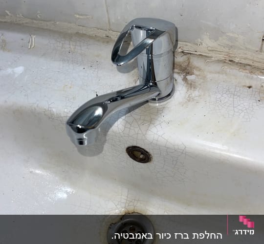ברז כרום על כיור עם סתימות ולכלוך